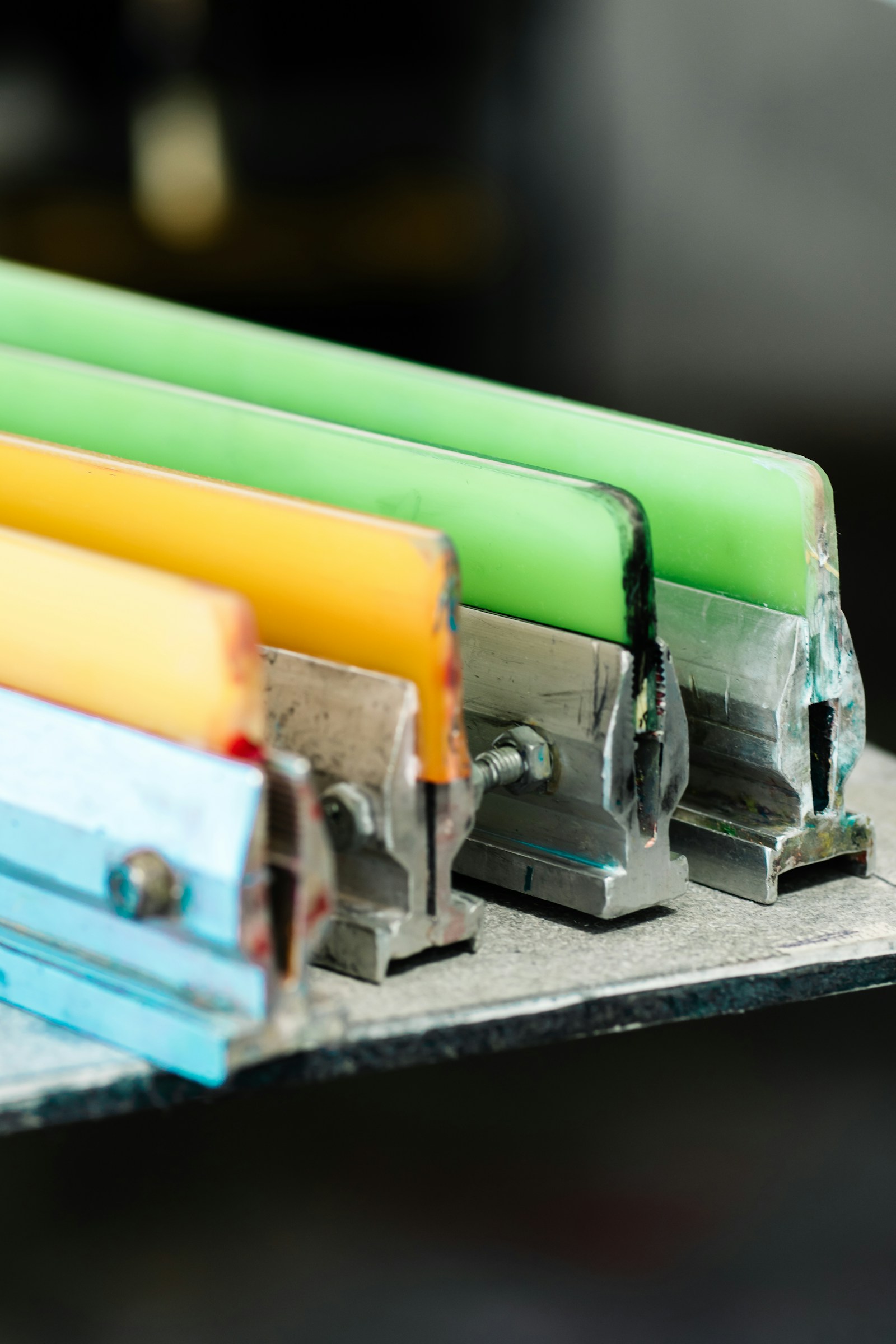 Colorful squeegees lined up on a bench in the Orange County studio
