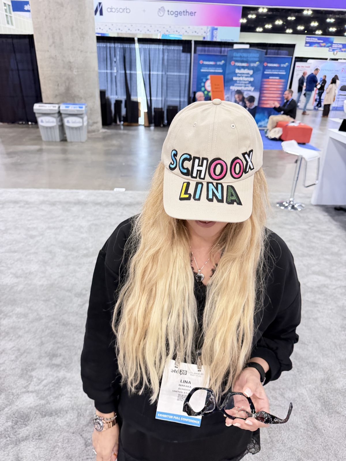 Guest showing off a tan baseball cap finished with colorful chenille letters at a personalization station