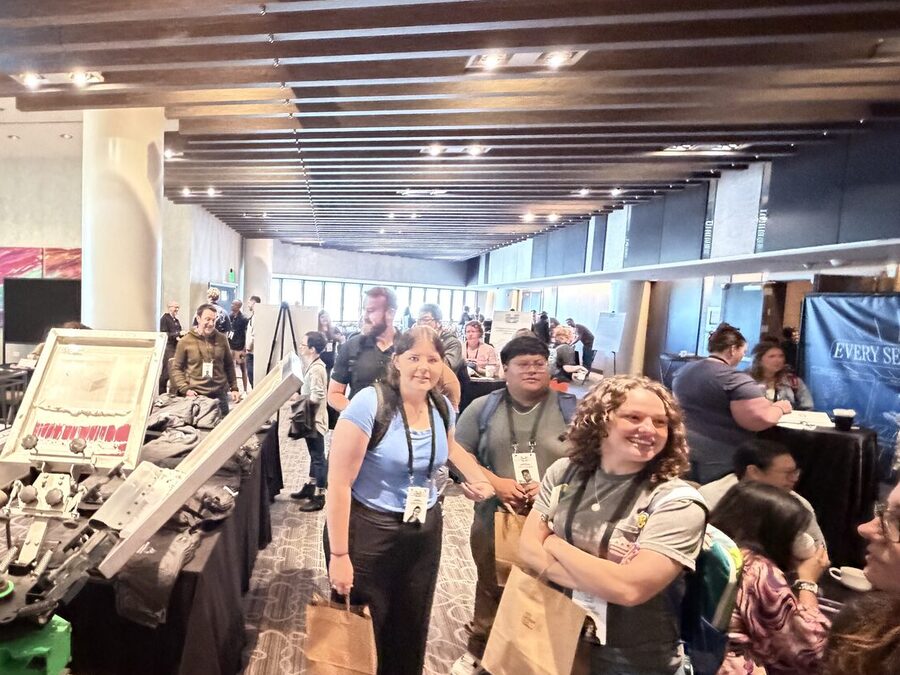 Conference guests carrying kraft gift bags through a hotel ballroom foyer